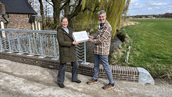 Gebiedsmanager Martijn Koobs ontvangt waterpen van Anouk van der Poll van de Waterambassade